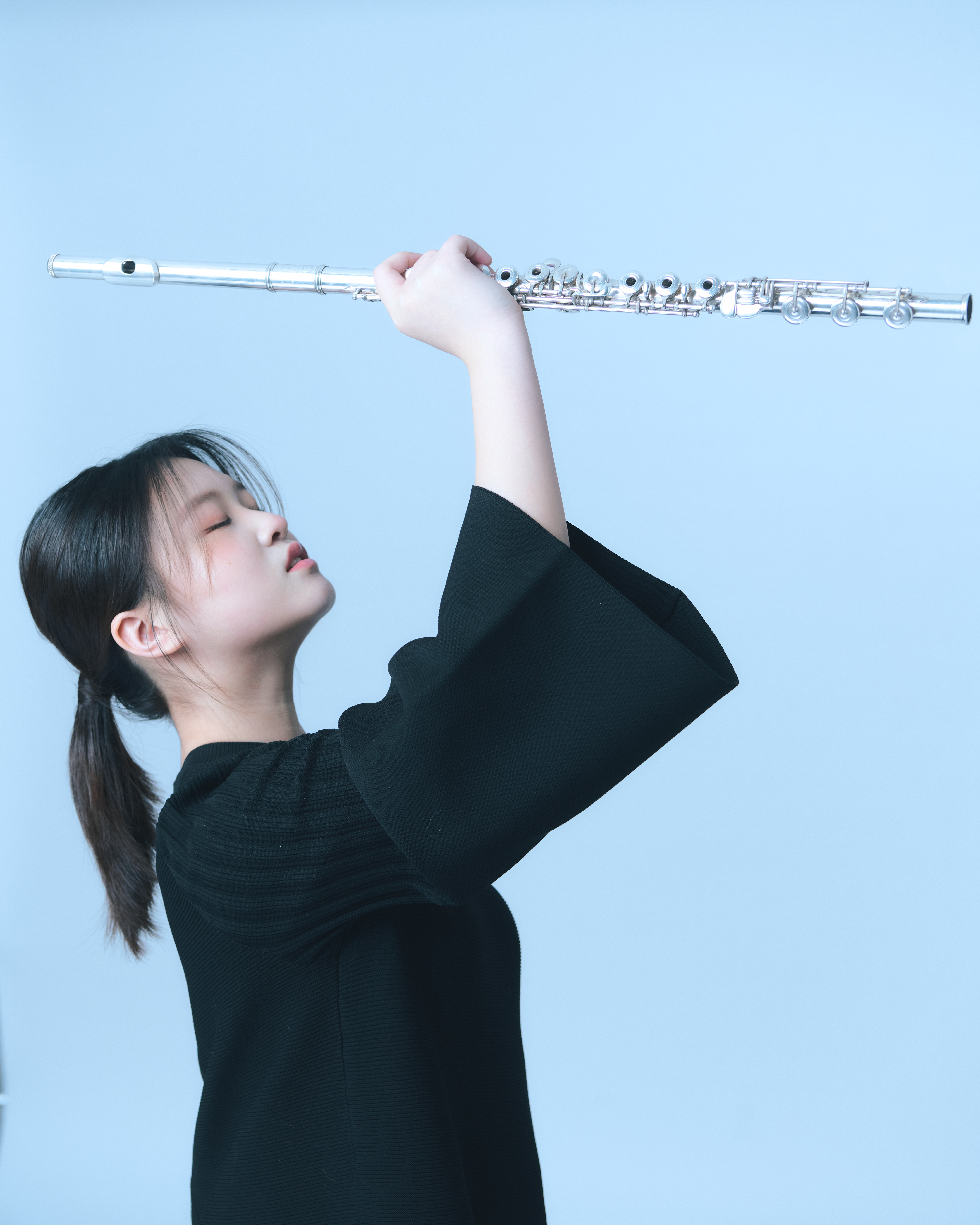 Schuwen Zheng holding a flute against a blue background